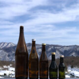 冬の雪景色の山川と5本の日本酒瓶